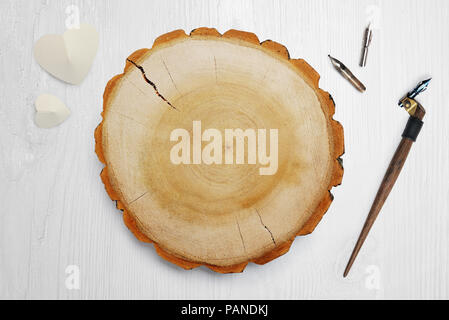 Plume calligraphique, se trouve à proximité d'un cercle en bois avec un papier blanc coeur. Mise à plat, haut voir photo maquette Banque D'Images