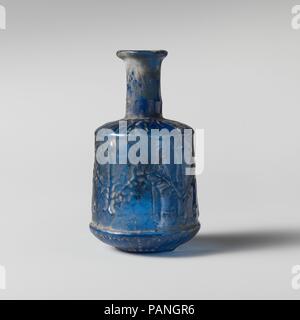 Bouteille en verre. Culture : Roman. Dimensions : H. : 3 1/4 in. (8,3 cm). Date : 1er siècle de notre ère. Cobalt Translucide bleu. Rebord, partiellement repliées et au cou, cylindrique, avec un léger renflement horizontal line vers la base ; l'épaule convexe en pente avec des extra-ridge ; corps cylindrique avec côtés légèrement vers le bas avec l'expansion horizontale de premier ridge ci-dessous ; undercurve circulaire convexe ; fond creux avec le centre de patron. Deux coutures moule exécuté à partir de la partie inférieure du cou vers le bas côtés vers le haut de la crête horizontale importante ; une section en forme de coupe forme la partie inférieure du corps et de la base. Pour l'épaule Banque D'Images