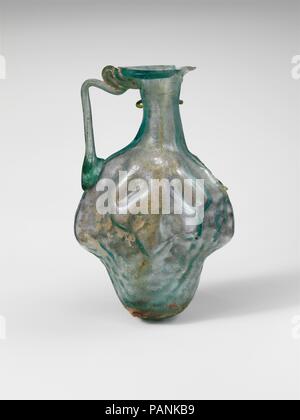 Le flacon en verre en forme de grappe de raisins. Culture : Roman. Dimensions : H. : 3 3/8 in. (8,6 cm). Date : 2ème-3ème siècle de notre ère. Vert, bleu translucide avec poignée de même couleur. Rim dépliées, bas, rond, et dans la bouche ; brûlage ; cou cylindrique difformes, les côtés concaves ; lentoid ; corps ; fond rond poignée tige attaché à bord de l'épaule dans un pad, établi à la verticale, tourné dans, et sur le dessous de la bouche et la jante. Marque de moule soulevées visible uniquement à la base du cou d'un côté, mais une seule couture du moule doit tourner autour du corps. Corps moulé dans la forme d'un tri-lobées, grappe de raisins avec Banque D'Images