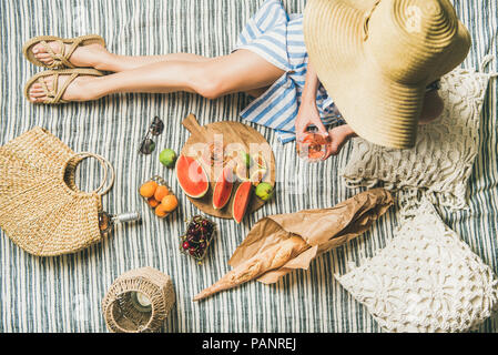 Pique-nique estival avec du vin dans les mains de womans, baguette, fruits Banque D'Images