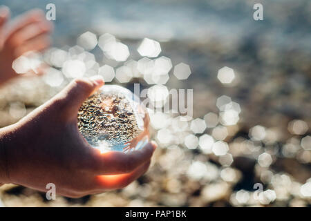 Boy's hand holding tansparent sphère sur un lac Banque D'Images
