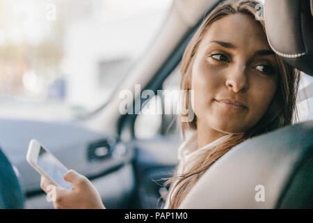 Young businesswoman sitting in car, using smartphone Banque D'Images