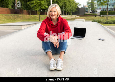 Senior woman wearing red hoodie Playing with laptop Banque D'Images