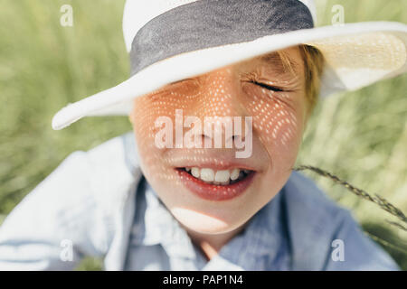 Garçon aux yeux clos portant un chapeau sitting in field Banque D'Images