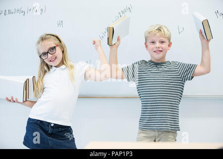 Portrait of happy lycéenne et écolier portant des livres dans la classe Banque D'Images