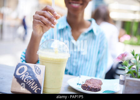 Woman drinking smoothie bio au café, vue partielle de la chaussée Banque D'Images
