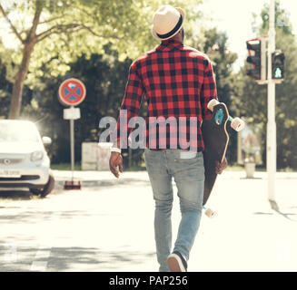 Jeune homme cool avec skateboard marcher dans la ville, Banque D'Images