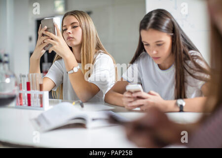 Les jeunes filles l'utilisation de téléphones cellulaires dans la classe de sciences Banque D'Images