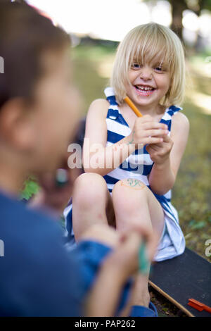 Portrait of laughing petite fille avec genou peint Banque D'Images