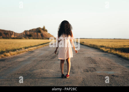 Young woman standing on country road, cachant son visage derrière les cheveux bruns Banque D'Images