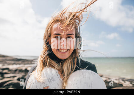 France, Bretagne, Landeda, portrait of smiling young woman holding parties d'un monde à l'autre Banque D'Images