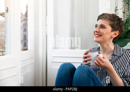 Happy woman sitting détendu au fenêtre, boire du café Banque D'Images