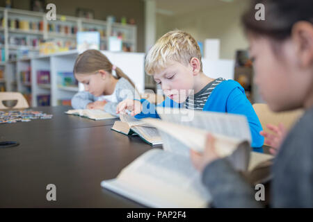 Les élèves à lire des livres sur la table à l'école de la salle de pause Banque D'Images