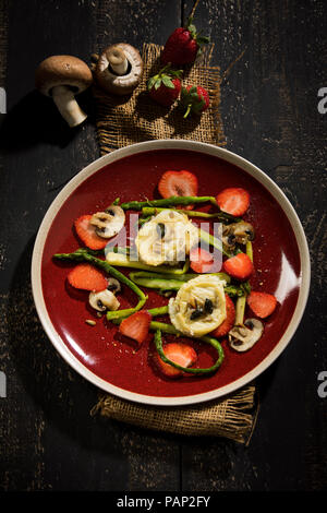 Salade aux asperges vertes, champignons, fromage de chèvre, fraises et noix de pin, grillées Banque D'Images