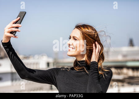 Portrait of smiling woman with smartphone selfies Banque D'Images