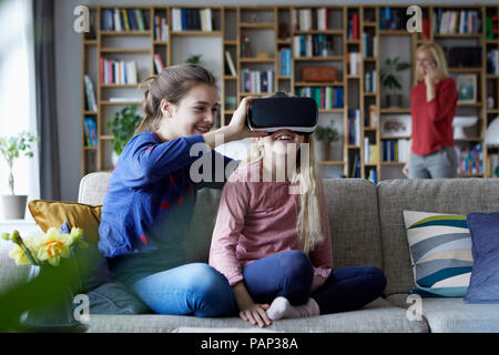 Sisters sitting on couch, jouant avec lunettes VR Banque D'Images