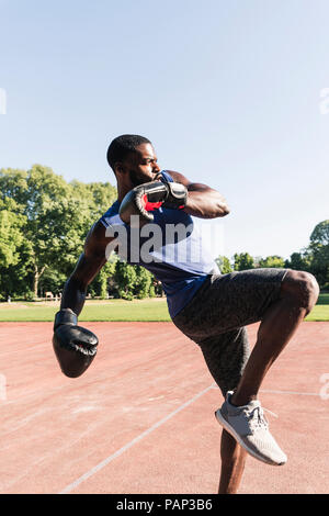 Jeune homme afro-boxe formation sur terrain de sport, à l'extérieur Banque D'Images