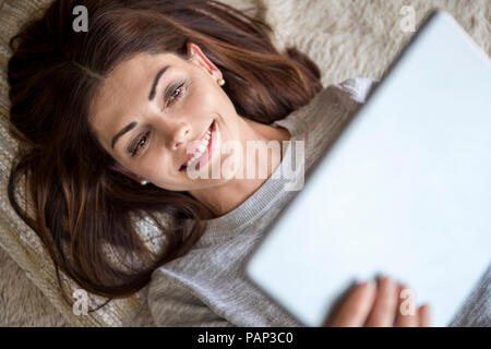 Smiling woman lying on tapis à l'aide d'une tablette Banque D'Images