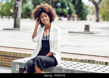 Portrait de jeune femme avec des cheveux bouclés assis sur un banc Banque D'Images