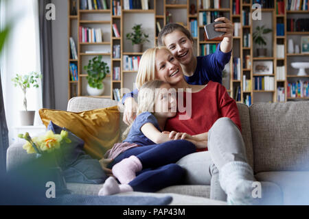 Mère et ses filles assis sur la table, en prenant vos autoportraits smartphone Banque D'Images