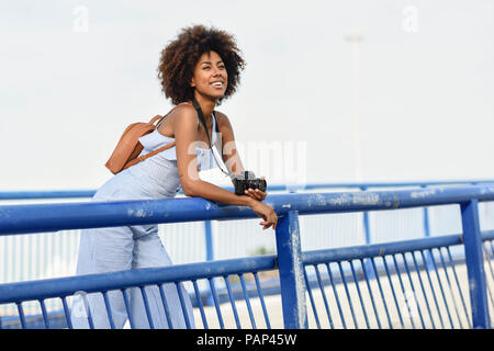 Portrait de jeune femme à la mode avec sac à dos et appareil photo sur un pont Banque D'Images