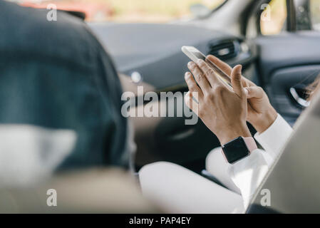 Young businesswoman sitting in car, using smartphone Banque D'Images