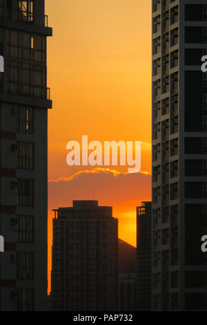 Fiery coucher du soleil orange entre les fenêtres des immeubles de grande hauteur à Pasig, Manille - Philippines Banque D'Images