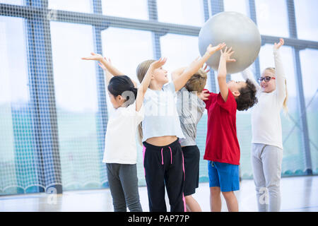 Les élèves la remise de ballon de gymnastique en cours de gymnastique Banque D'Images