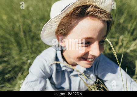 Portant un chapeau Happy boy sitting in field Banque D'Images