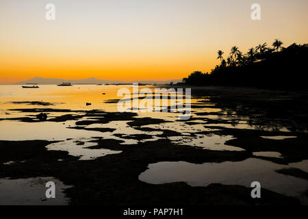 Fiery Coucher du soleil orange avec Tide Pools et palmiers le long des côtes rocheuses beach - Port Barton, Palawan - Philippines Banque D'Images