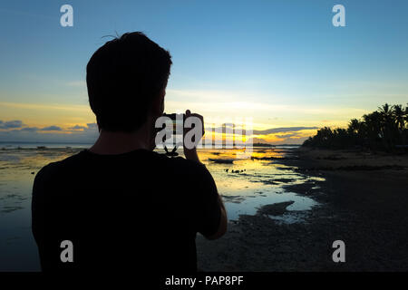 Homme photographe avec appareil photo, le tir dans le coucher du soleil sur une plage de l'île au cours de vacances - Aklan - Philippines, Boracay Banque D'Images