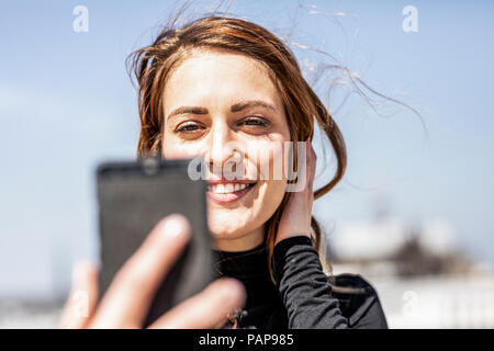 Portrait of smiling woman with smartphone selfies Banque D'Images