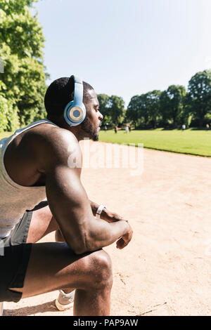 Souriante jeune athlète prenant une pause, portant des écouteurs, l'écoute de la musique Banque D'Images