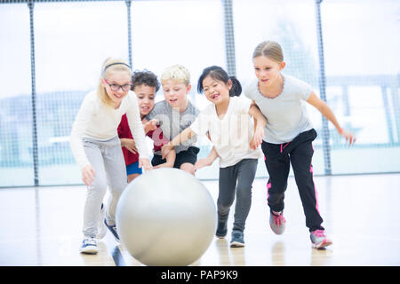 Les élèves heureux de jouer avec ballon de gymnastique en cours de gymnastique Banque D'Images