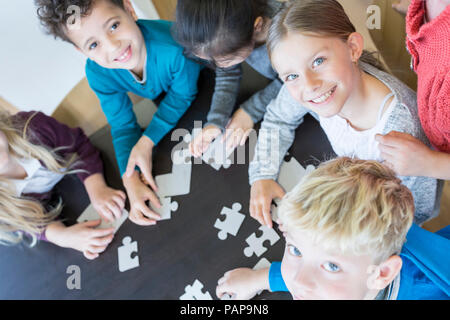 Portrait of smiling élèves jouant ensemble à l'école puzzle Banque D'Images