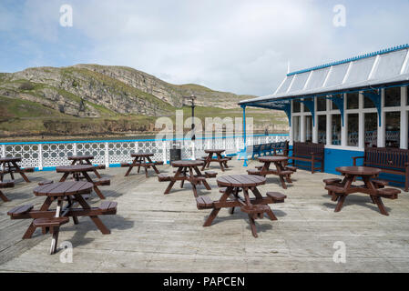 Des bancs de pique-nique sur la jetée de Llandudno avec le grand orme en arrière-plan, au nord du Pays de Galles, Royaume-Uni. Banque D'Images