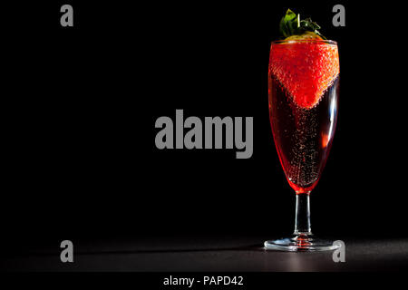 Célébration à boire. Verre de vin mousseux Champagne rose avec des fraises. Saint Valentin ou anniversaire parfait indulgence. Fond noir avec l'exemplaire sp Banque D'Images