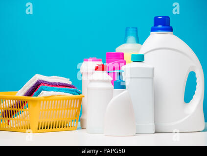 Photo de plusieurs bouteilles de produits de nettoyage et les serviettes colorées en orange panier isolé sur fond bleu Banque D'Images