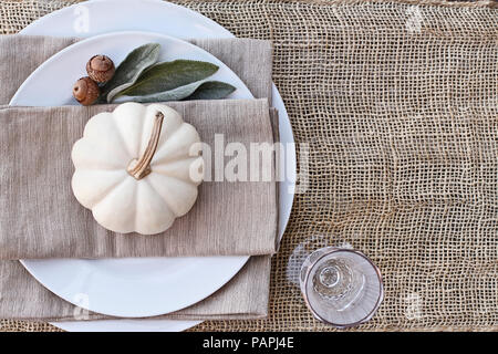 L'action de grâce ou Halloween place setting with mini citrouilles blanches, les oreilles d'agneau et de glands, feuilles de jute sur table. Banque D'Images