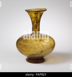Bouteille en verre. Culture : Roman. Dimensions : H. 6 11/16 in. (17 cm). Date : 4ème-5ème siècle de notre ère. Jaune translucide à teinte verte. Jante inégale, fissurés et sol, en entonnoir du cou, épaule horizontale ; large ; corps bulbeux, appliqué, outsplayed base faible. à pied tubulaire éversée, bague faite en repliant et en bas convexe ;. Intacte, sauf pour petite puce dans la jante ; de nombreux et piqûre quelques bulles plus grandes ; et ternir légèrement irisés, des correctifs d'émail-comme l'altération brunâtre. Vase jaune avec corps rond et cou en forme d'entonnoir. Musée : Metropolitan Museum of Art, New York, USA. Banque D'Images