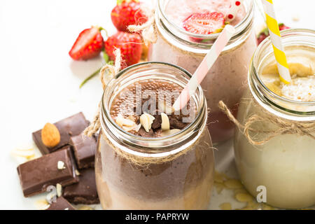 Ensemble de milkshake en pots. La banane, chocolat et fraise milkshakes aux noix et noix de coco. Dessert d'été. Alimentation saine. Banque D'Images