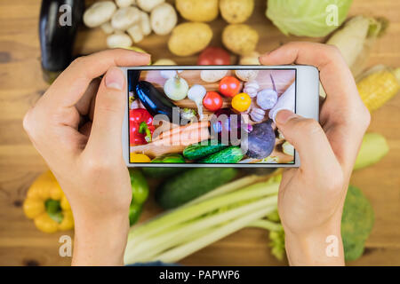 La prise de photo de légumes biologiques frais sur la table de bois rustique, vue du dessus. Close-up of female hands photographie télévision laïcs de Vega naturelles cultivés localement Banque D'Images