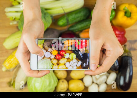 La prise de photo de légumes biologiques frais sur la table de bois rustique, vue du dessus. Close-up of female hands photographie télévision laïcs de Vega naturelles cultivés localement Banque D'Images