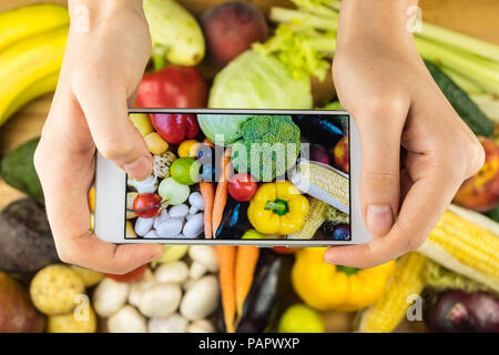 La prise de photo de fruits et légumes frais biologiques sur table en bois rustique, vue du dessus. Close-up of female hands télévision Photographie de laïcs na cultivés localement Banque D'Images