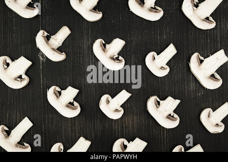 Tranches de champignons blancs sur fond rustique en bois noir, vue du dessus. Mise à plat de champignons blanc modèle sur table Banque D'Images