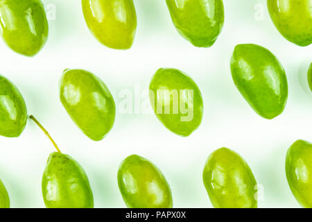 Vue de dessus de motif lumineux olives vertes fraîches sur fond blanc. En plongée des olives de multiples Banque D'Images