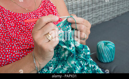 Femme engagée dans le crochet d'un chandail de laine bleu Banque D'Images
