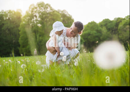 Mère et fille avec blowball sur prairie en été Banque D'Images