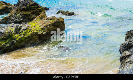 La baie de Godrevy, Cornwall, calme close up colorful bord de l'eau éclaboussant éclabousser légèrement contre les rochers. Banque D'Images