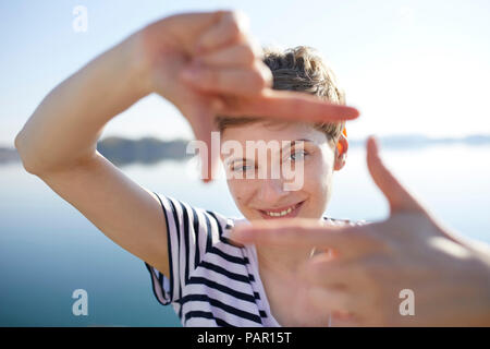 Portrait de femme en face du lac de l'élaboration de cadre avec ses doigts Banque D'Images